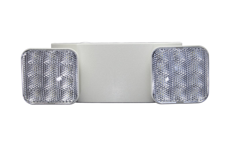 The Shine LED Indoor Emergency Light - Dual Head features a rectangular, white fixture equipped with two square, multi-faceted lens lamps on either side. The clear, textured lenses effectively diffuse light to provide broad illumination. With a battery backup that ensures over 90 minutes of runtime and flame-retardant housing, this straightforward and utilitarian fixture is ideal for industrial or commercial use.