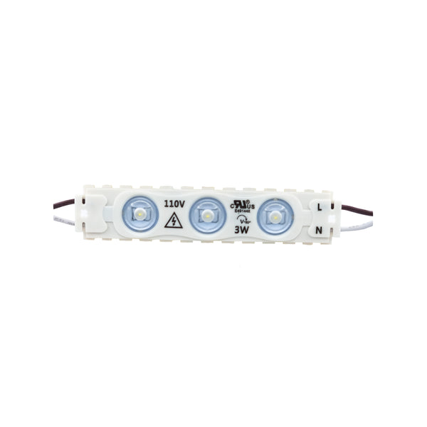 The Shine LED Single Color LED Module Direct AC 110V - 3W - 6000K - 55 Ft- IP67 features a small, rectangular design with three dome-shaped LED lights encased in a white housing. The module indicates "110V" and "3W" on its surface, with wires extending from both ends. Ideal for indoor and outdoor lighting, it includes self-adhesive tape for easy installation. Each pack contains 100 pieces.